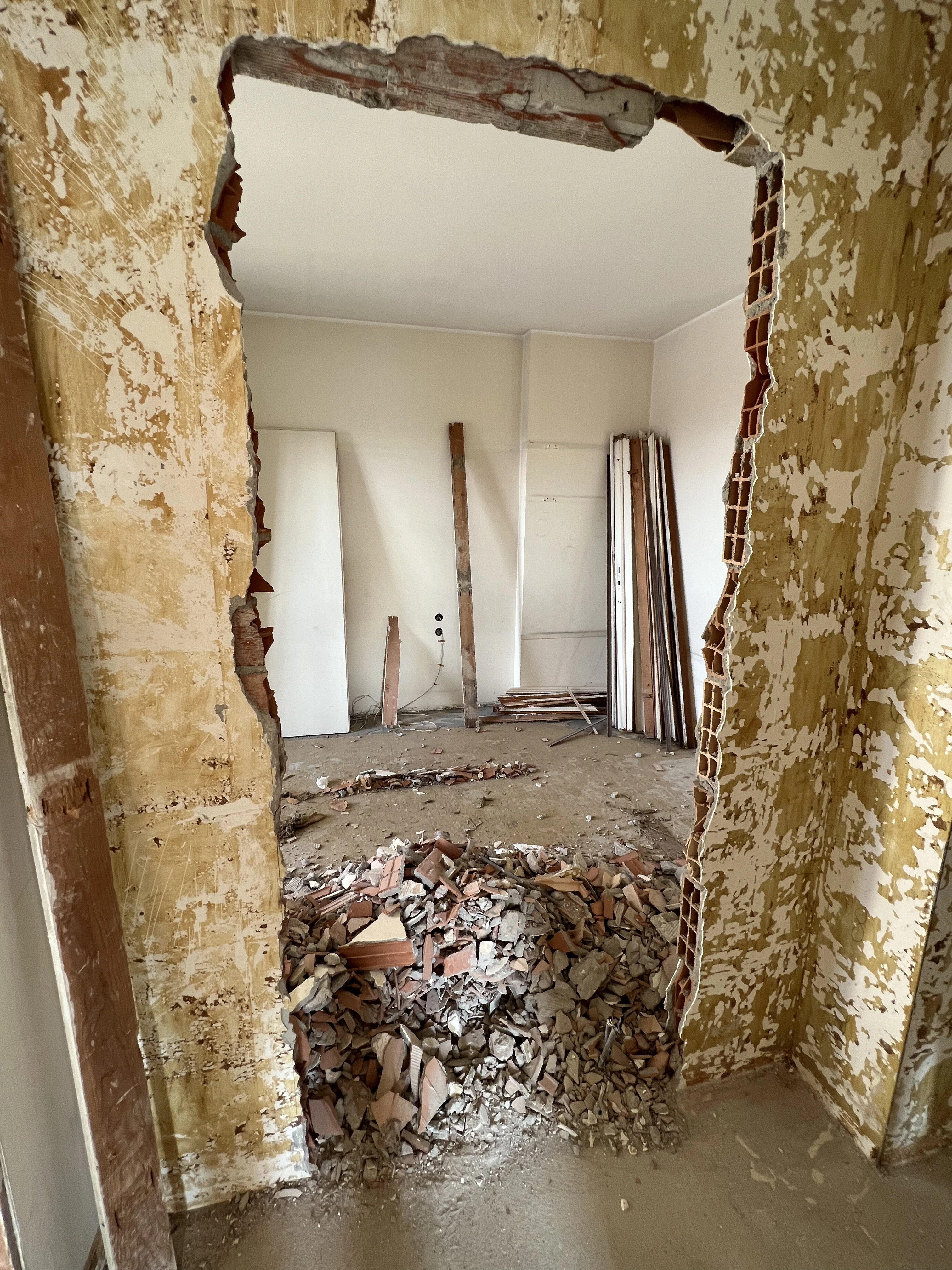 Interno in ristrutturazione con controsoffitto stuccato, cavi elettrici sospesi e muratura esposta dopo le demolizioni