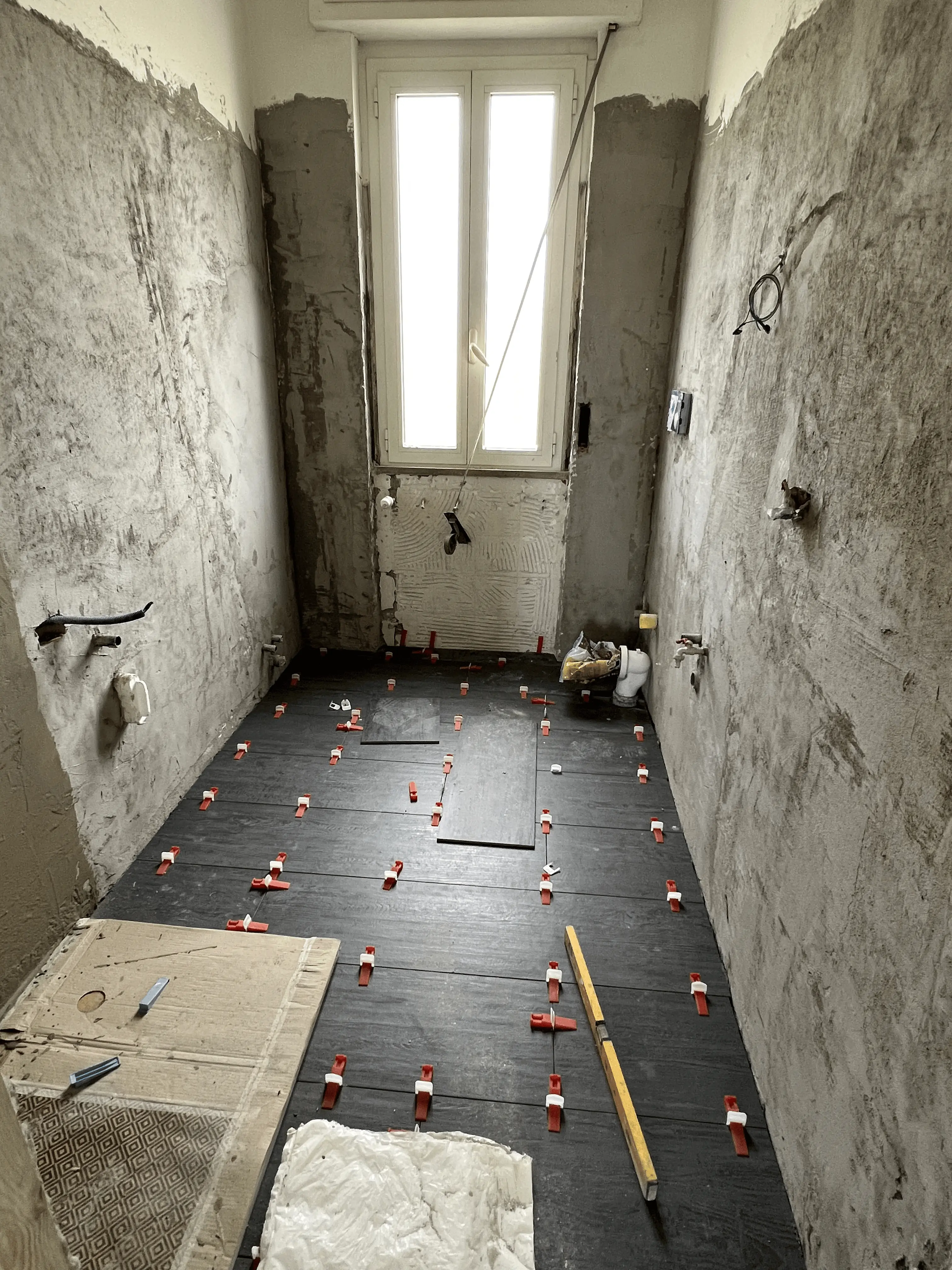 Soffitto in cartongesso stuccato con cavi elettrici sospesi e pareti grezze durante lavori di rivestimento