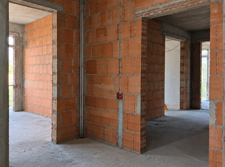 Soffitto in cartongesso stuccato con cavi elettrici pendenti e pareti grezze durante opere murarie