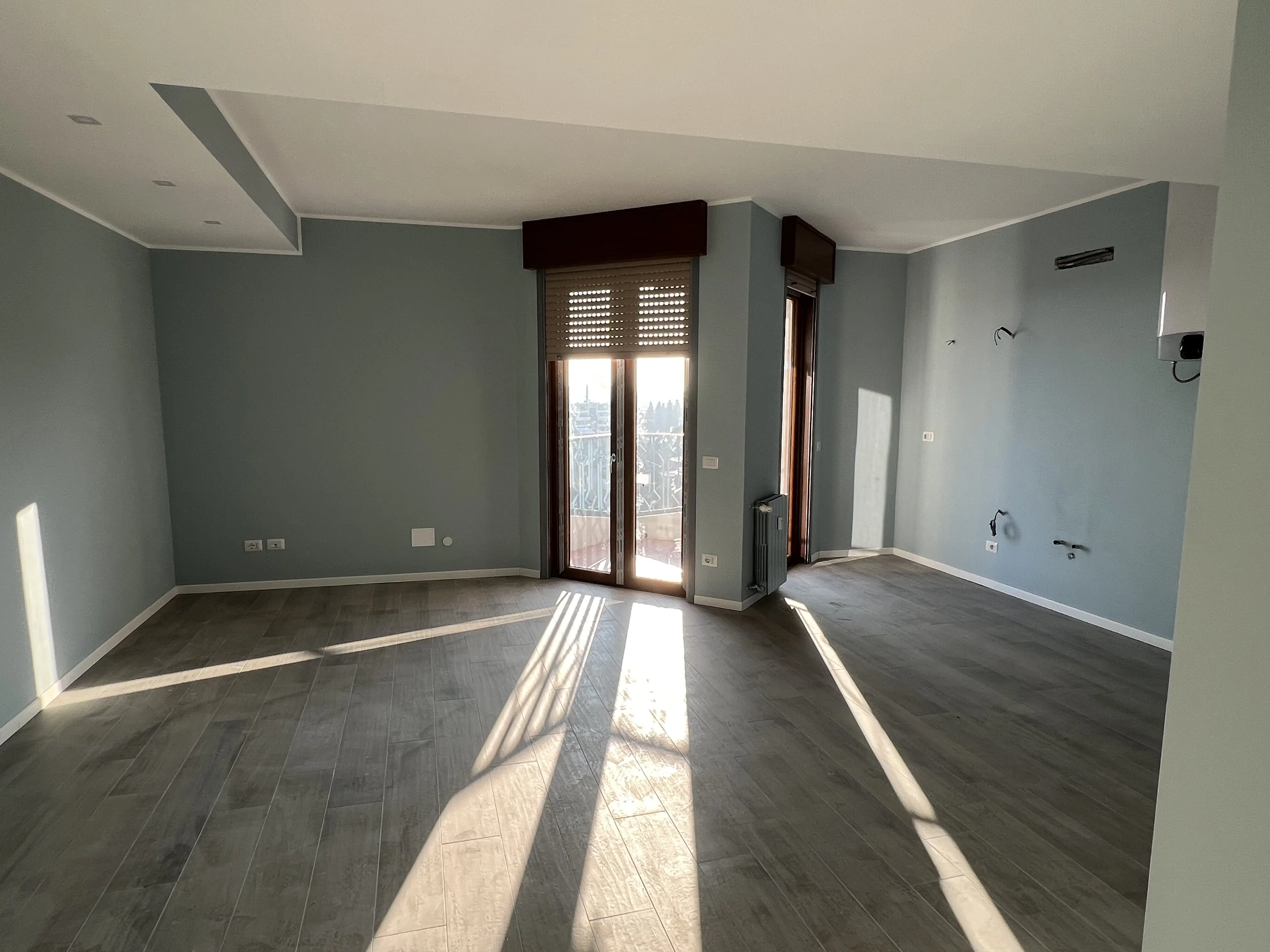 Preparazione per tinteggiature e verniciature su soffitto in cartongesso stuccato, con cavi elettrici pendenti.