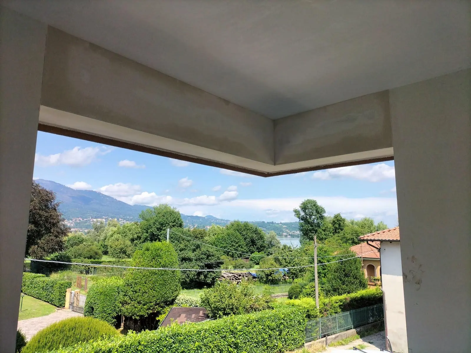 Controsoffitto in cartongesso e pareti in lavorazione attorno a un'ampia apertura con vista sul verde.