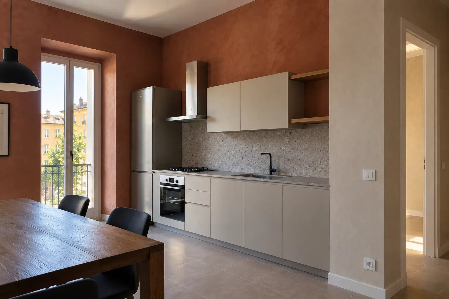 Cucina moderna con pareti in terracotta, mobili chiari e tavolo in legno accanto alla finestra.