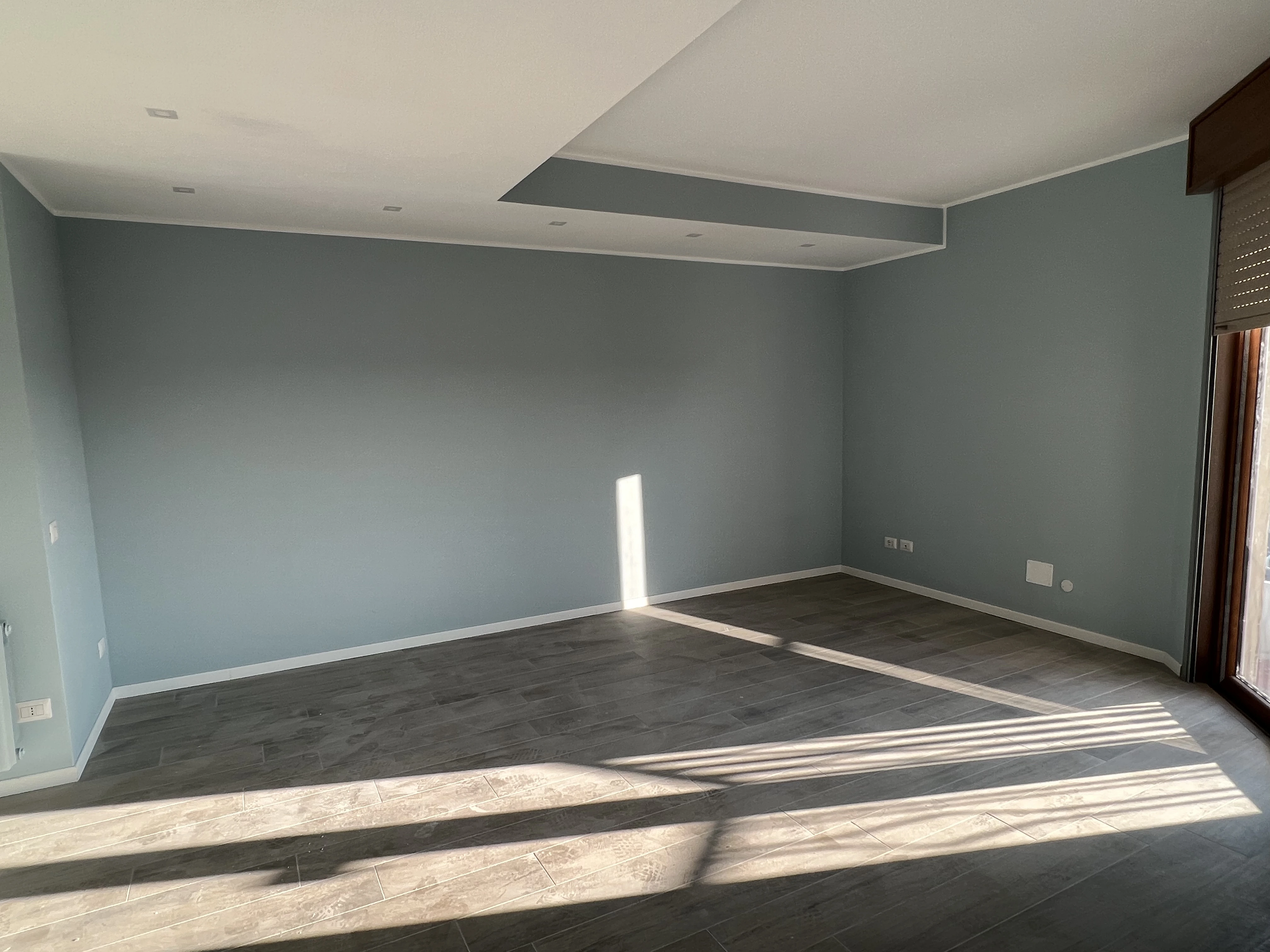 Soggiorno tinteggiato in azzurro con controsoffitto, realizzato da Maestro Edilizia | Ristrutturazione Casa a Milano.