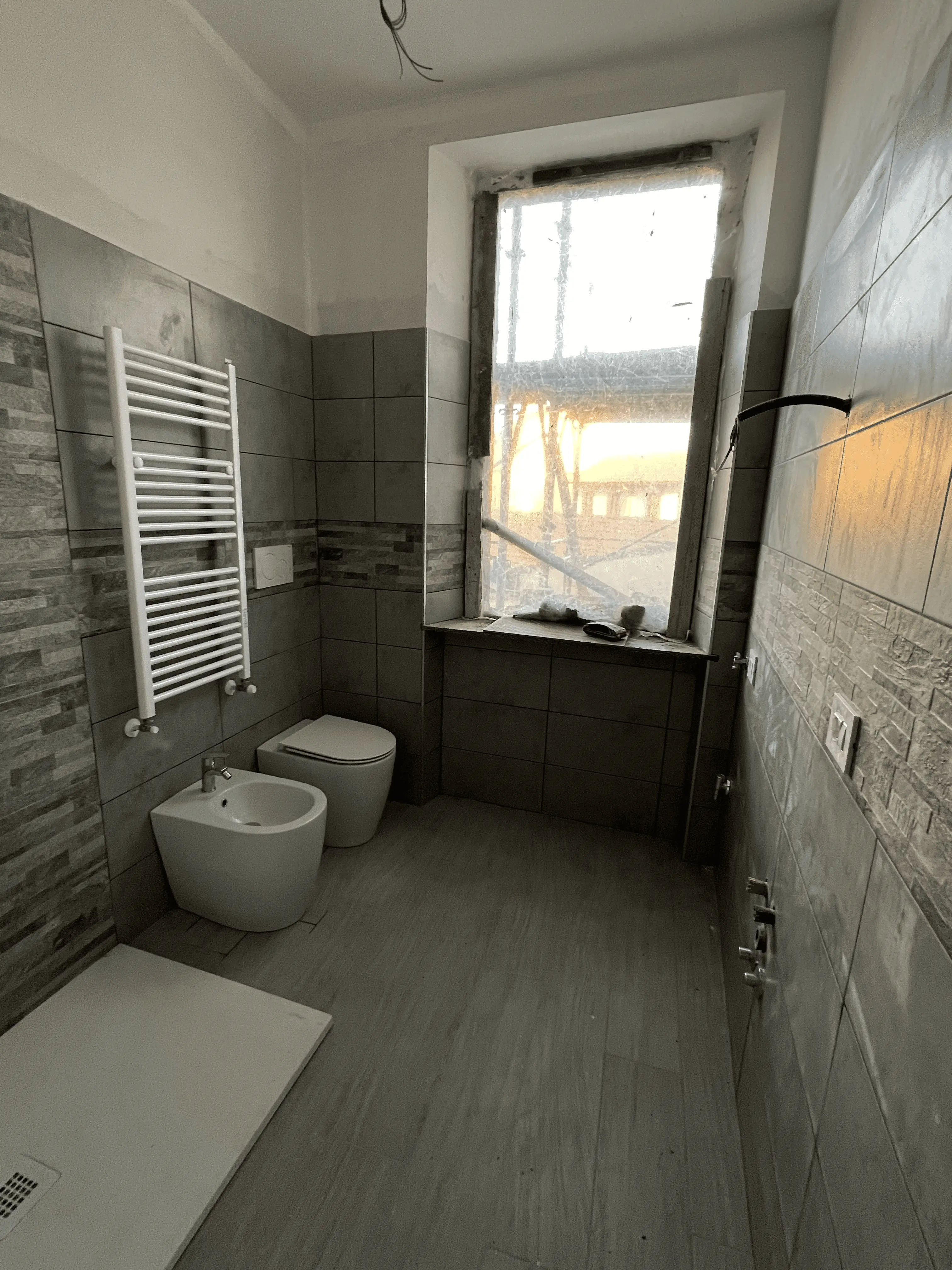 Bagno con piastrelle 3D e pavimento effetto legno, ristrutturato da Maestro Edilizia | Ristrutturazione Casa a Milano.