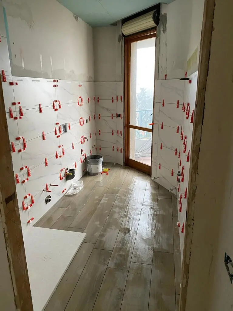 Posa di rivestimenti e pavimento in un bagno ristrutturato da Maestro Edilizia | Ristrutturazione Casa a Milano.