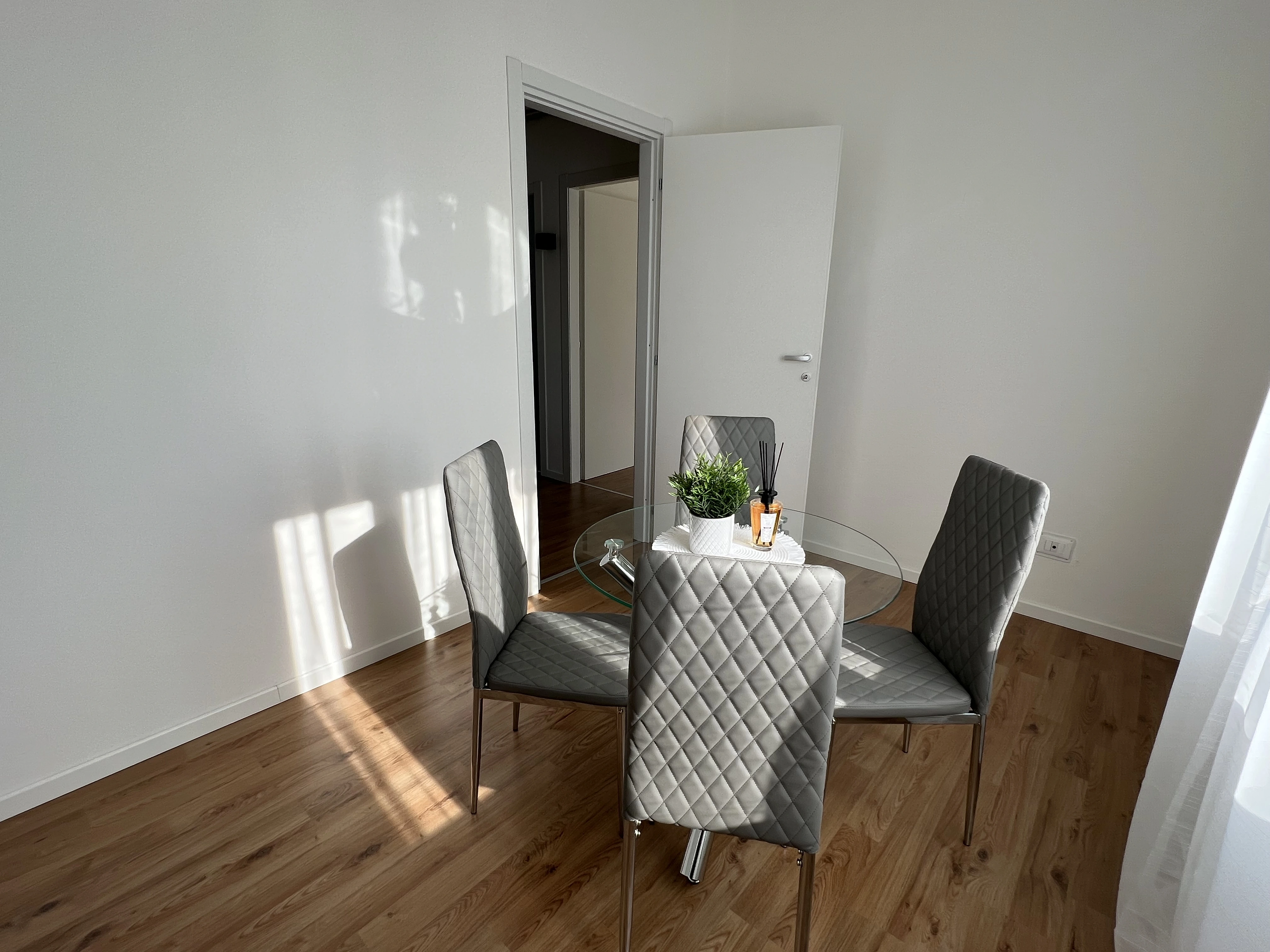 Sala da pranzo ristrutturata con parquet e tavolo in vetro da Maestro Edilizia | Ristrutturazione Casa a Milano.