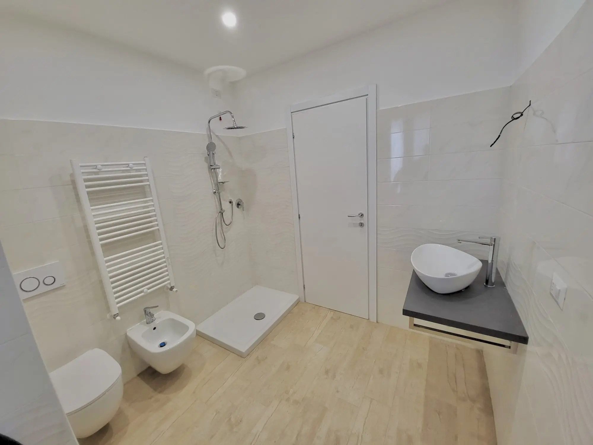 Bagno ristrutturato con doccia in vetro e piastrelle effetto marmo da Maestro Edilizia | Ristrutturazione Casa a Milano.