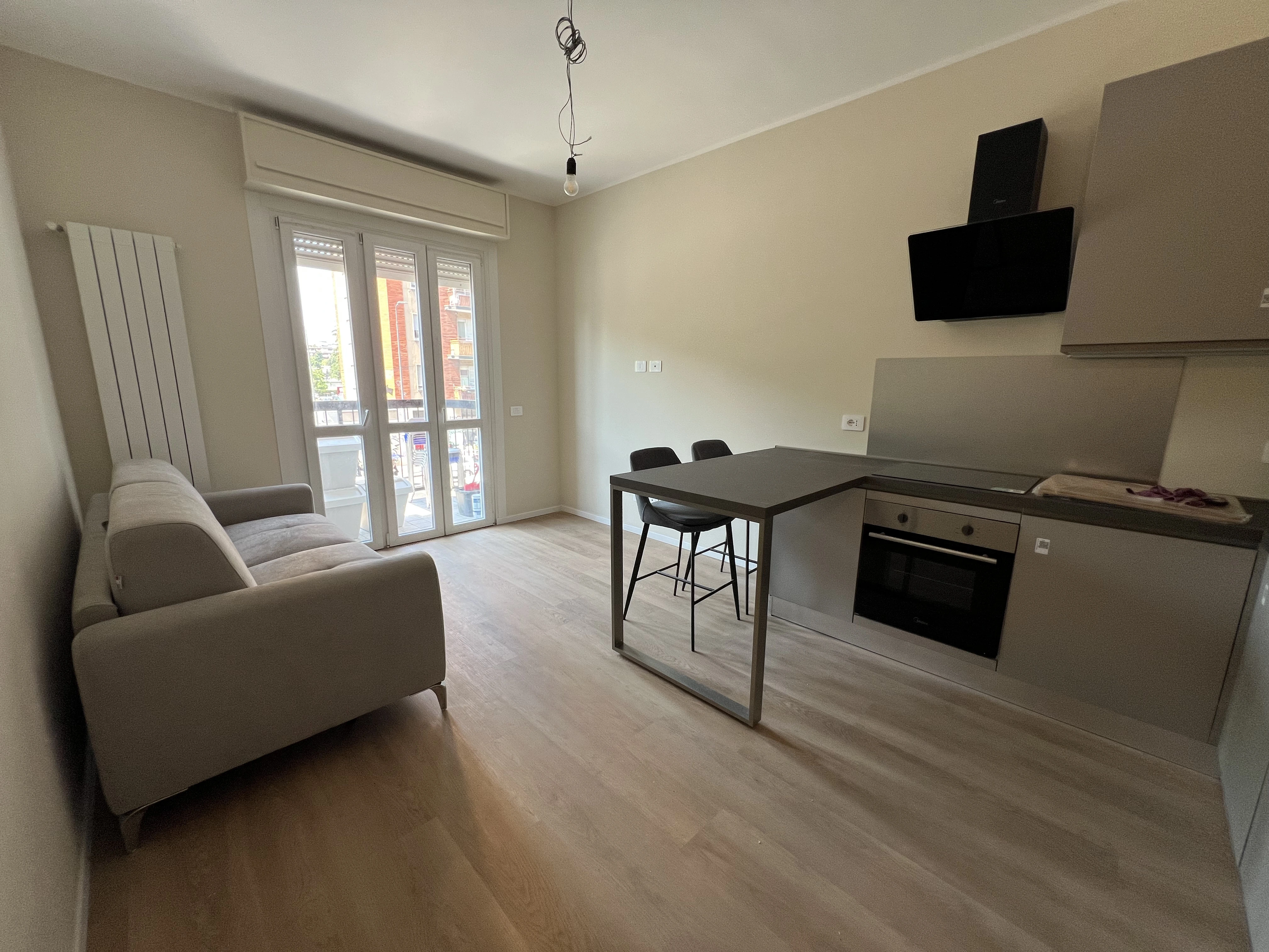 Soggiorno con cucina a vista ristrutturato da Maestro Edilizia | Ristrutturazione Casa a Milano.