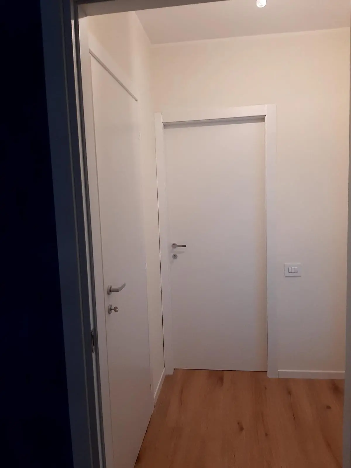 Corridoio ristrutturato con porte bianche e parquet da Maestro Edilizia | Ristrutturazione Casa a Milano.