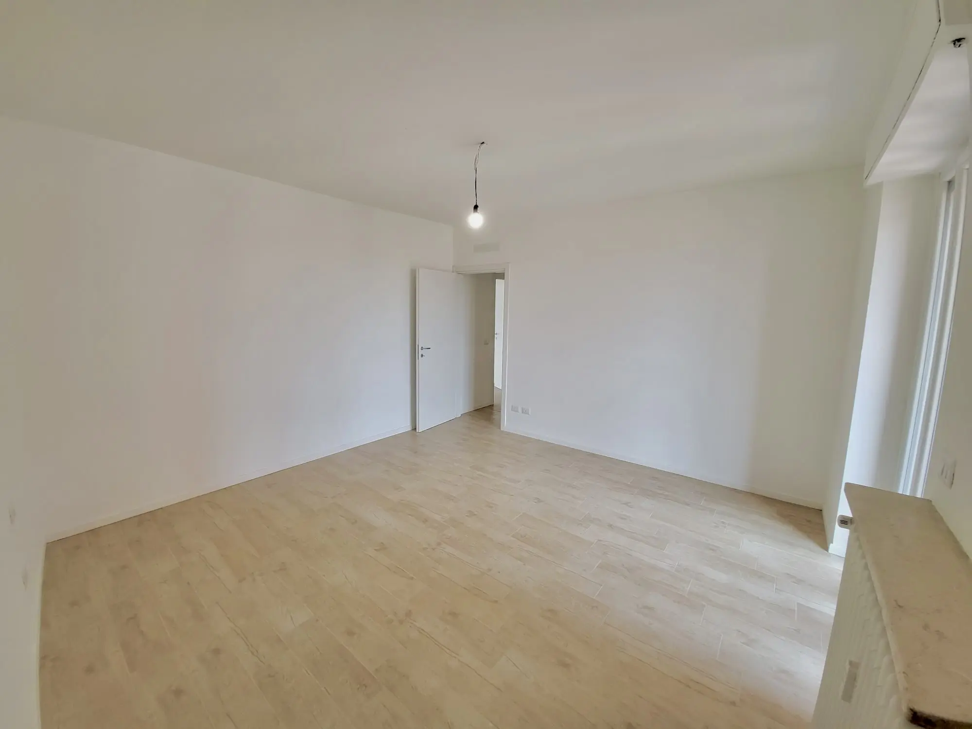 Camera ristrutturata con pareti bianche e pavimento in legno da Maestro Edilizia | Ristrutturazione Casa a Milano.
