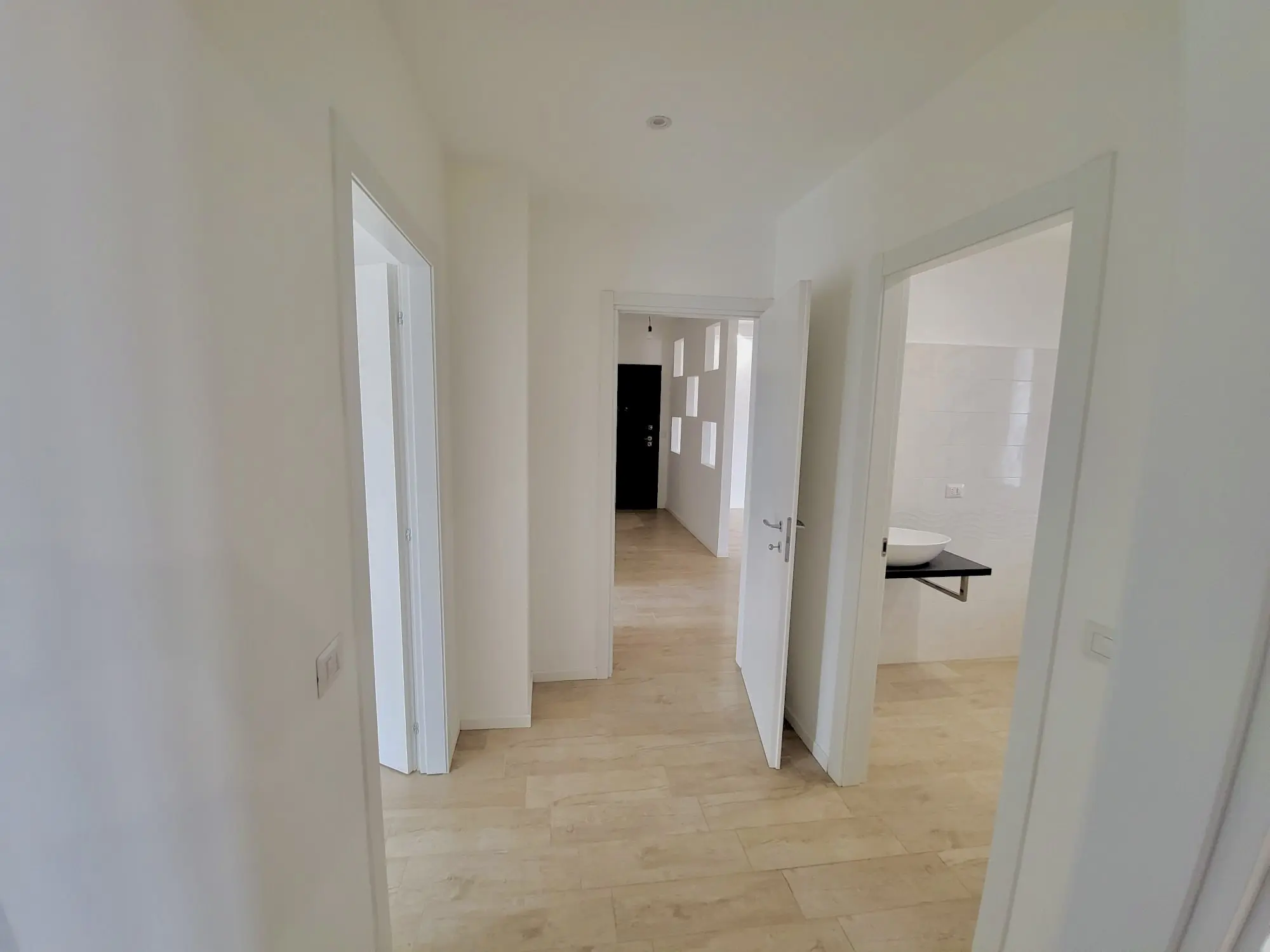 Corridoio ristrutturato con porte bianche e pavimento chiaro da Maestro Edilizia | Ristrutturazione Casa a Milano.