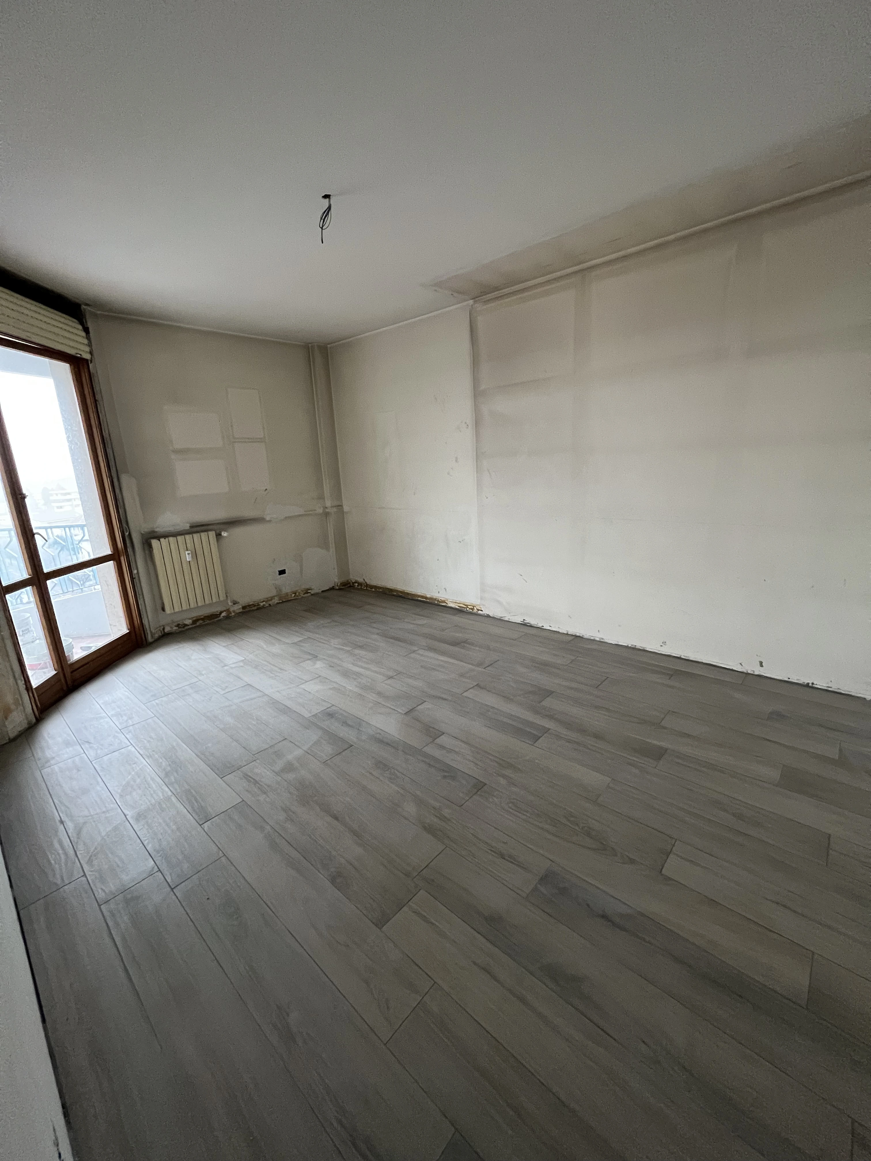 Stanza in ristrutturazione con pavimento effetto legno di Maestro Edilizia | Ristrutturazione Casa a Milano.