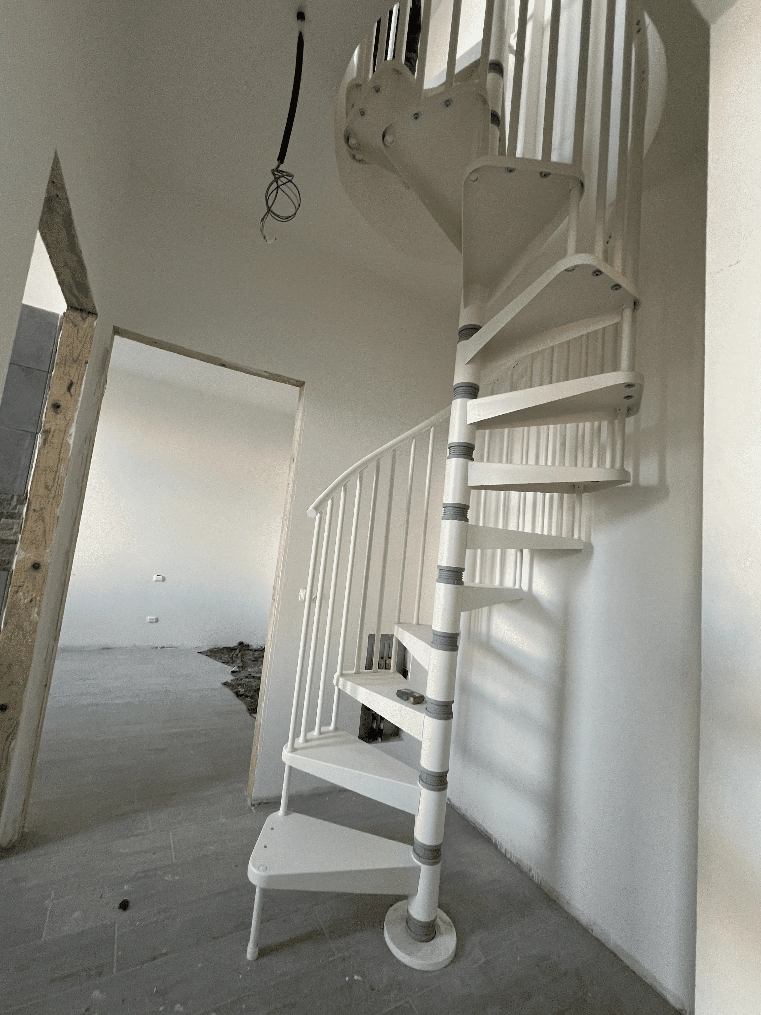 Scala a chiocciola bianca in una casa ristrutturata da Maestro Edilizia | Ristrutturazione Casa a Milano.