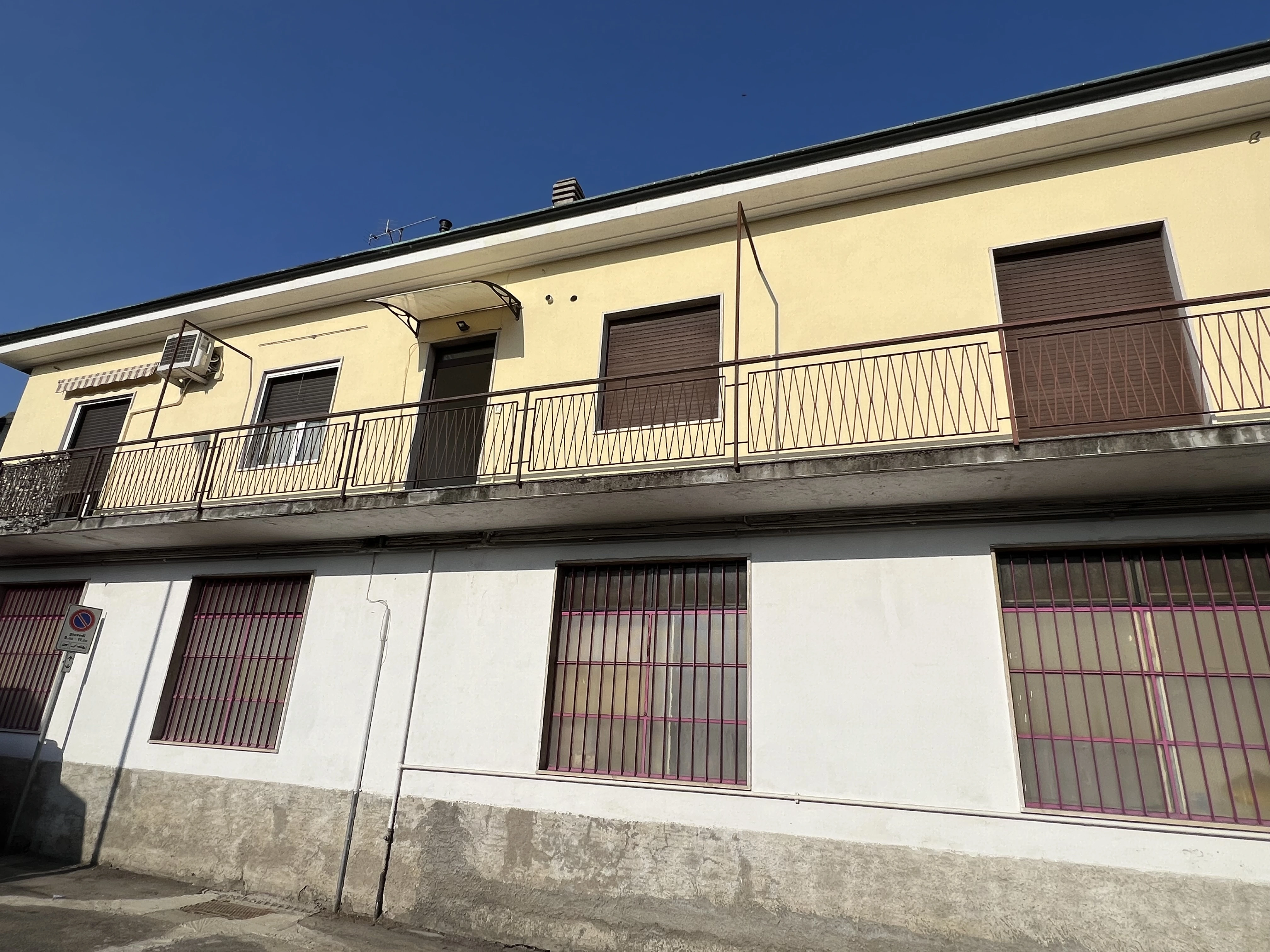 Facciata gialla con balconi e tetto piano di Maestro Edilizia | Ristrutturazione Casa a Milano.